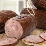 Kiełbasa żywiecka, wędzona, z widocznym przekrojem i plastrami na chlebie.