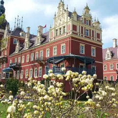 Piękny park mużakowski zwiedzanie w otoczeniu czerwonego pałacu i kwitnących krzewów.