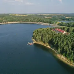 Malownicze jezioro Chańcza otoczone lasem, z hotelem i pomostem.
