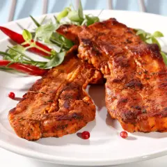 Dwa soczyste plastry boczek na grilla, przyprawione ziołami i podane z papryczkami chili.