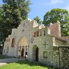 Kamienna brama z krzyżami i figurą świętego, przypominająca wejście do puszczy dulowskiej.