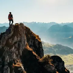 Wspinacz na szczycie skalistej góry, podziwiający panoramę. Widać, ile się wchodzi na rysy, by osiągnąć taki widok.