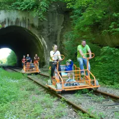 Rodzina na drezynach w Bieszczadach, przejeżdża obok tunelu kolejowego.