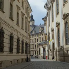 Wąska, brukowana uliczka prowadzi do serca starego rynku we Wrocławiu. Po bokach piętrzą się zabytkowe kamienice z ozdobnymi fasadami i kratami w oknach.