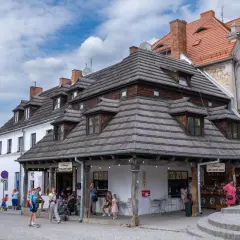 Tętniący życiem rynek w Kazimierzu Dolnym. Ludzie spacerują, kupują lody i gofry, podziwiając zabytkową architekturę.
