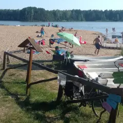 Słoneczny dzień nad zalewem zielona. Ludzie odpoczywają na plaży, kąpią się, a obok stoją łódki.