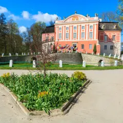 Kurozwęki atrakcje: barokowy pałac otoczony parkiem, z kwitnącymi tulipanami przed wejściem.