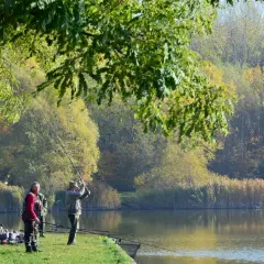 Wędkarze nad jednym z **trzech stawów** w jesiennej scenerii.