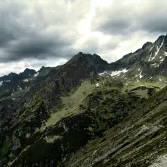 Kamienista droga pod reglami w Tatrach, z widokiem na skaliste szczyty i pochmurne niebo.