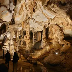 Dwie osoby zwiedzają imponujące jaskinie w Polsce, podziwiając stalaktyty i stalagmity.