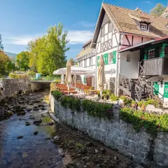 Urokliwy deptak w Szklarskiej Porębie nad kamienistym potokiem, z kawiarnią i restauracją z ogródkiem.