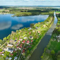 Malownicze jezioro Pławniowice z kanałem i zabudowaniami w otoczeniu zieleni.