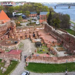 Ruiny zamku bierzgłowskiego z cegły, z widokiem na Wisłę i most.