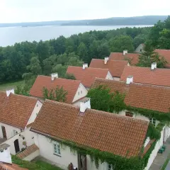 Urokliwe, pokryte czerwonymi dachówkami domy w Sejnach, otoczone zielenią, z widokiem na jezioro. Atrakcje regionu.