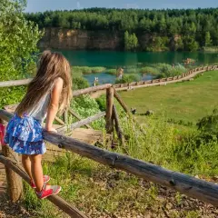 Dziewczynka podziwia widok na zalew w Parku Gródek Jaworzno. Warto sprawdzić park gródek jaworzno cena wstępu, by cieszyć się tym miejscem.
