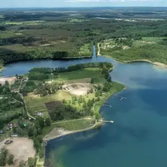 Malownicze jezioro Niesłysz otoczone lasami, z widocznymi domkami letniskowymi i pomostami.