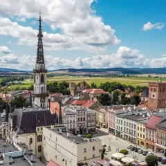 Widok na rynek i wieżę ratuszową w Ząbkowicach Śląskich. W tle pola i góry.