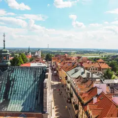 Widok z góry na urokliwy sandomierz rynek z brukowaną uliczką, kamieniczkami i kościelnymi wieżami w tle.