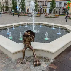 Żaba z parasolką siedzi przy fontannie na rynku w Bielsku-Białej.
