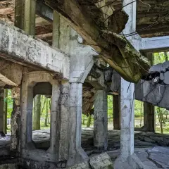 Ruiny koszar na Westerplatte podczas zwiedzania. Zniszczone betonowe konstrukcje i widok na drzewa.