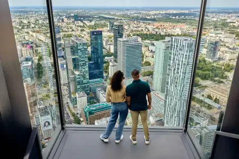 Para podziwia panoramę Warszawy z okna, widząc jej nowoczesne wieżowce i z daleka Pałac Kultury. Wysokość robi wrażenie.