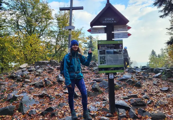 Uśmiechnięta turystka na szczycie Łysicy, 614 m n.p.m. Jesienne liście i kamienie wokół.