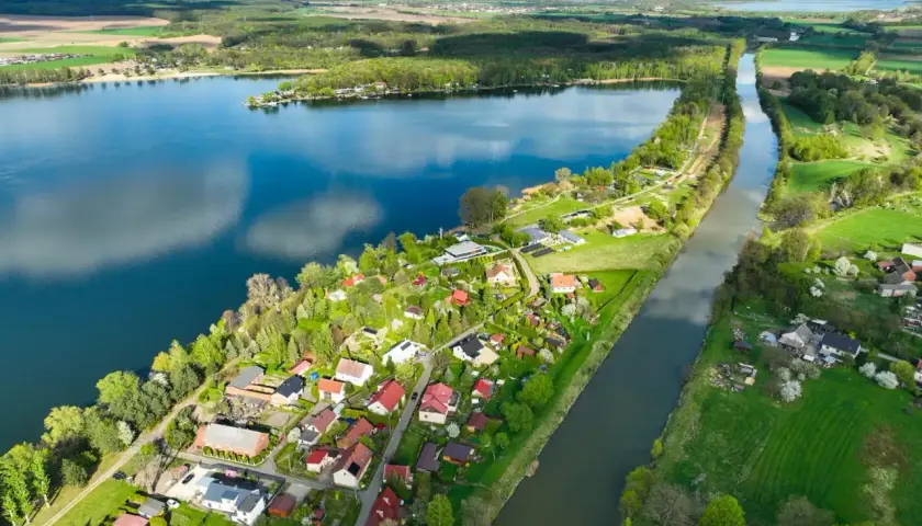 Malownicze jezioro Pławniowice z kanałem i zabudowaniami w otoczeniu zieleni.