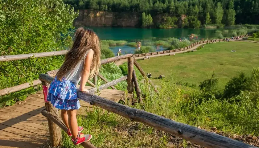 Dziewczynka podziwia widok na zalew w Parku Gródek Jaworzno. Warto sprawdzić park gródek jaworzno cena wstępu, by cieszyć się tym miejscem.