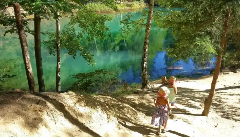 Dwie dziewczynki w słomkowych kapeluszach odkrywają piękne, turkusowe jezioro. To świetne atrakcje dla dzieci na Dolnym Śląsku.