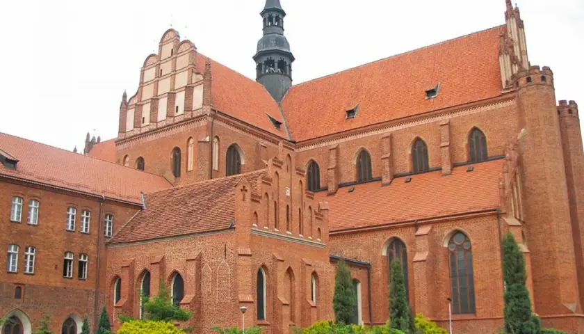 Imponująca ceglana katedra w Pelplinie z charakterystycznymi dachami i wieżą.