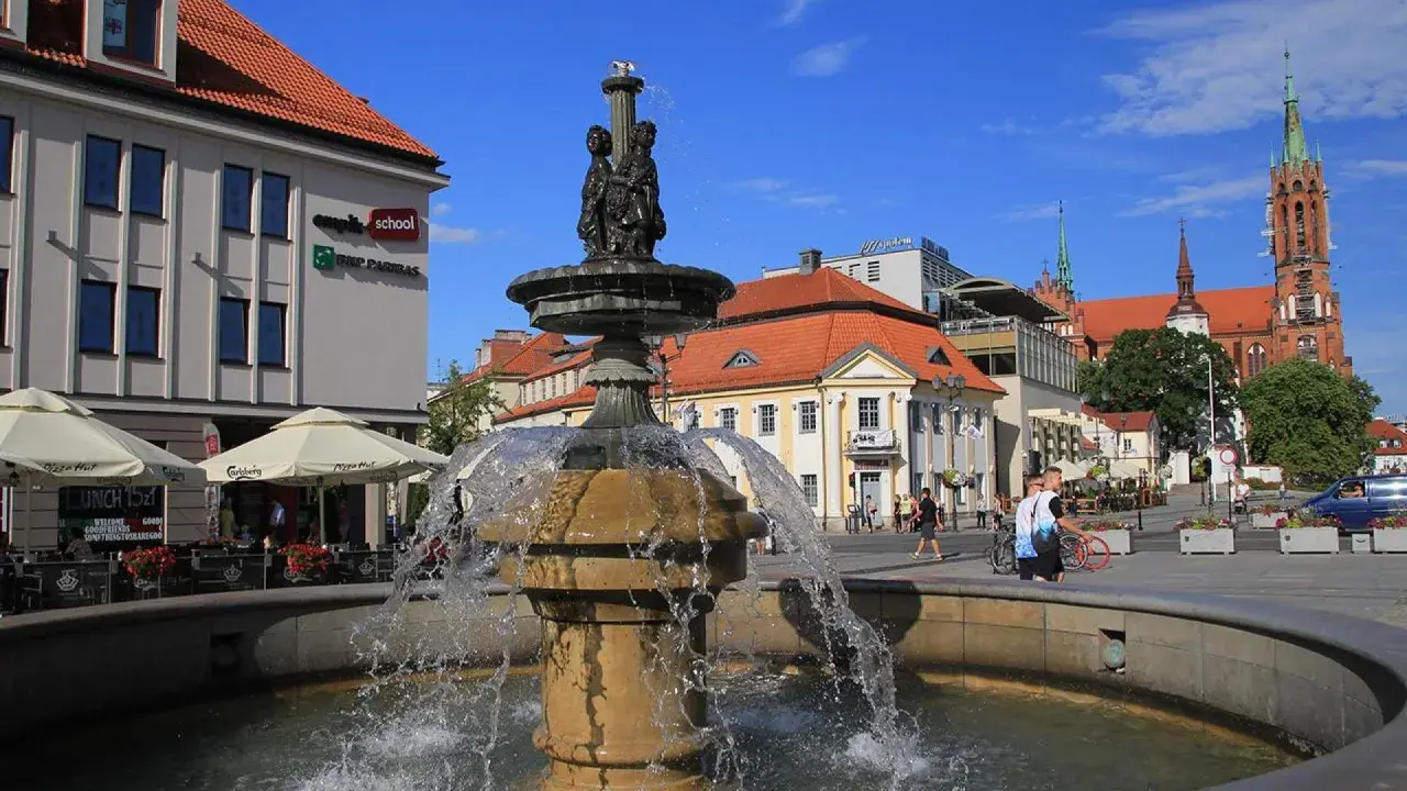 Fontanna na Rynku Kościuszki w Białymstoku, otoczona kawiarniami i zabytkową architekturą.