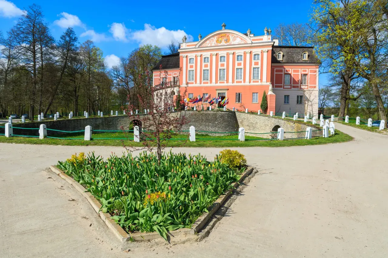 Kurozwęki atrakcje: barokowy pałac otoczony parkiem, z kwitnącymi tulipanami przed wejściem.