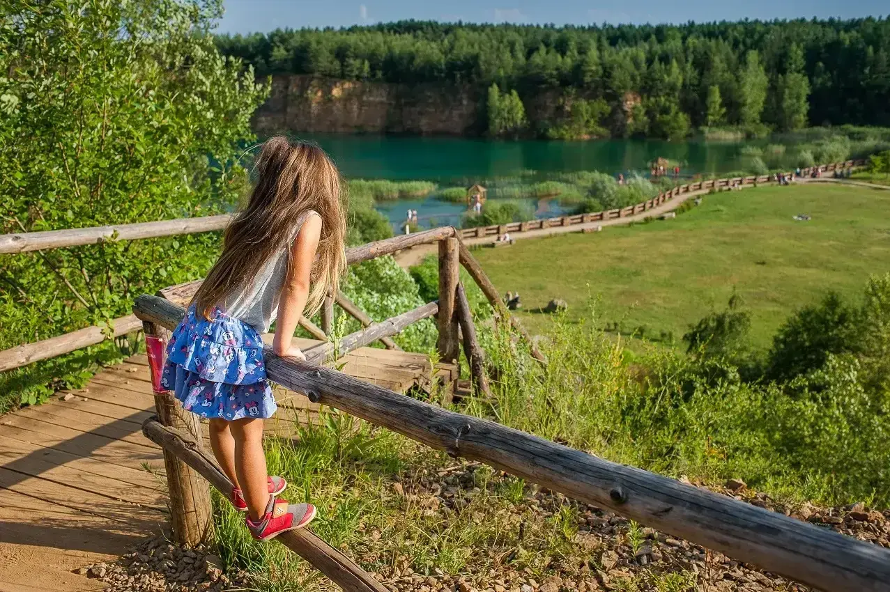 Dziewczynka podziwia widok na zalew w Parku Gródek Jaworzno. Warto sprawdzić park gródek jaworzno cena wstępu, by cieszyć się tym miejscem.
