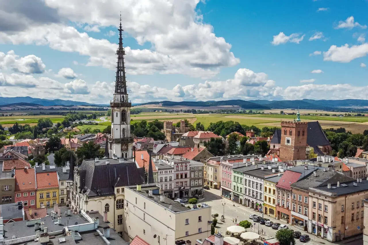 Widok na rynek i wieżę ratuszową w Ząbkowicach Śląskich. W tle pola i góry.