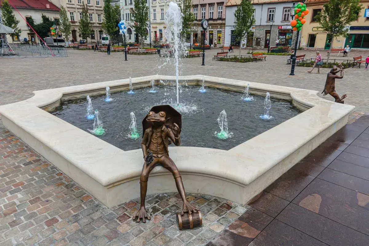 Żaba z parasolką siedzi przy fontannie na rynku w Bielsku-Białej.