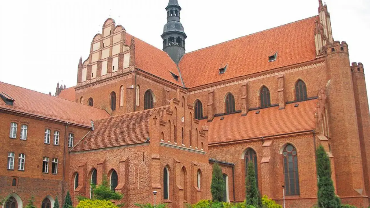 Imponująca ceglana katedra w Pelplinie z charakterystycznymi dachami i wieżą.