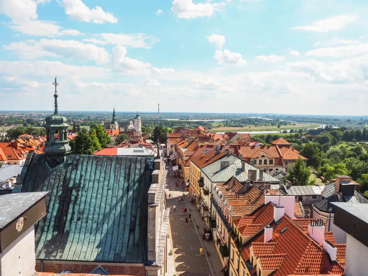 Widok na urokliwy sandomierz rynek z dachu kościoła. Kamienice z czerwonymi dachami i brukowana uliczka pełna spacerowiczów.
