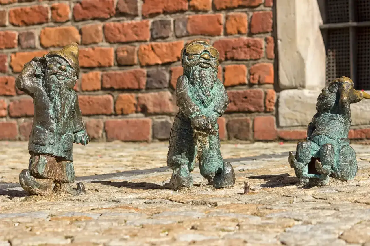 Trzy krasnale we Wrocławiu. Jeden pozdrawia, drugi w okularach, trzeci na wózku. Ciekawe ciekawostki o Wrocławiu czekają na odkrycie!