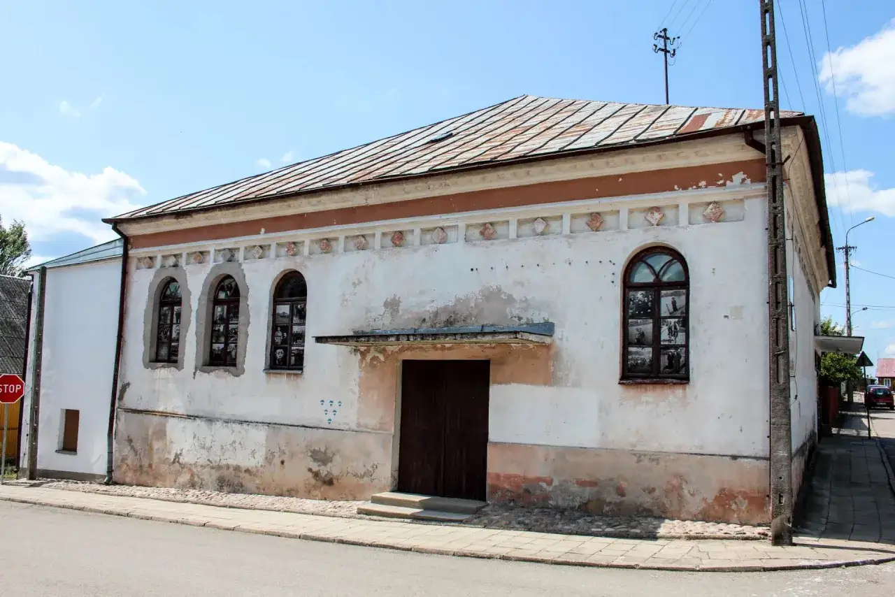 Stara synagoga w Krynkach, jedna z lokalnych atrakcji, z oknami ozdobionymi historycznymi fotografiami.
