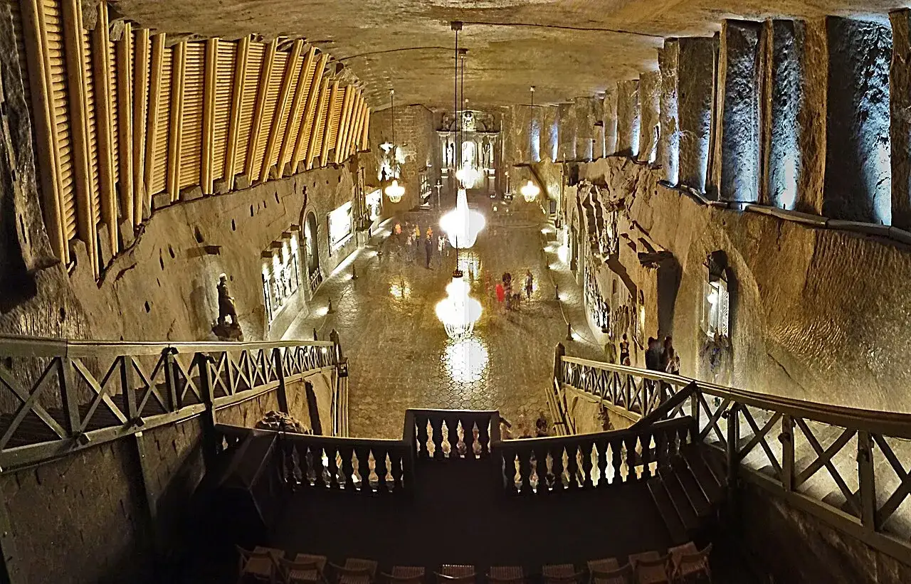 Wnętrze kopalni soli w Wieliczce, z oświetlonymi rzeźbami i żyrandolami, zachwyca turystów.