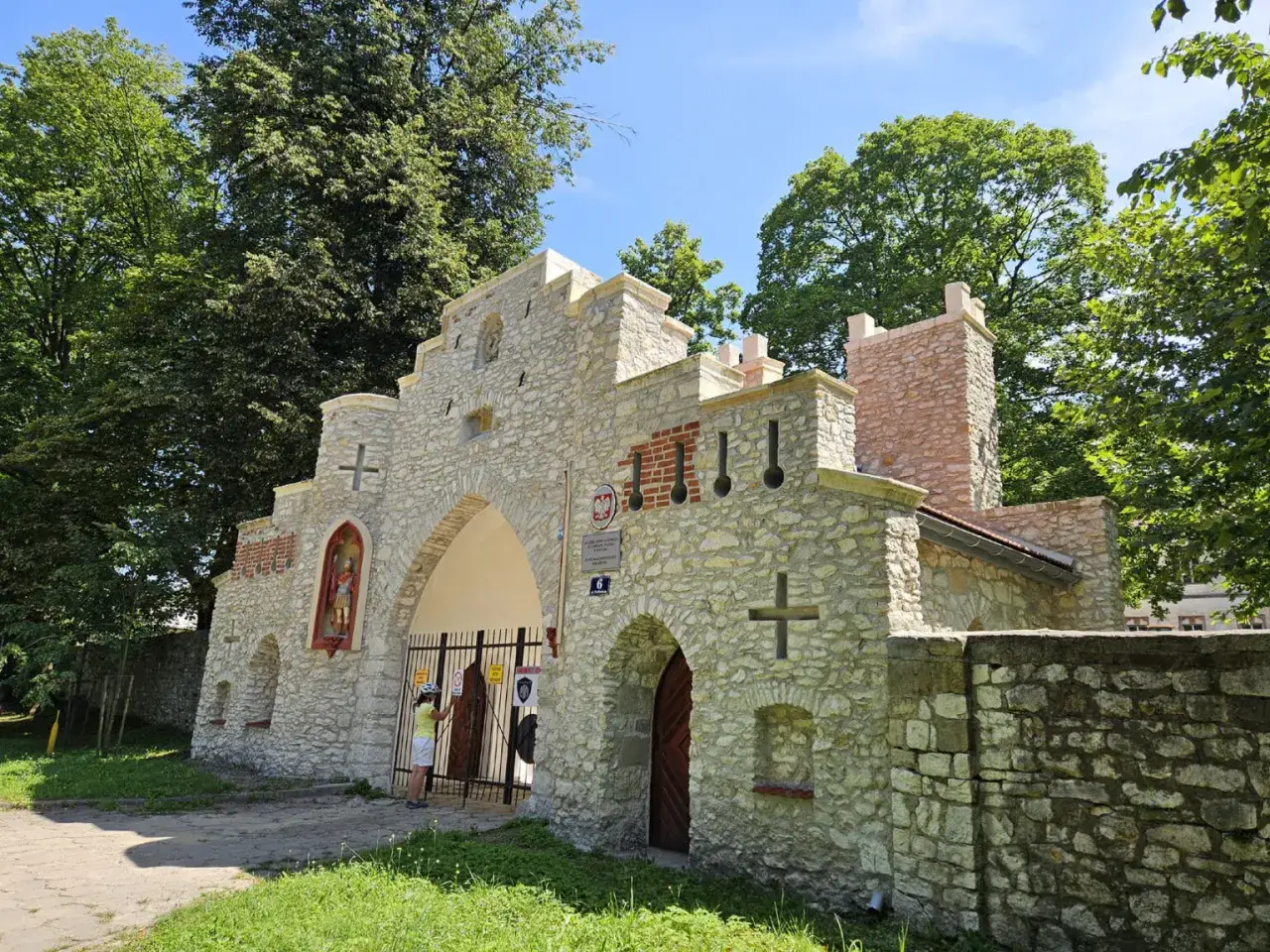 Kamienny wjazd do Puszczy Dulowskiej, ozdobiony krzyżami i figurą świętego.
