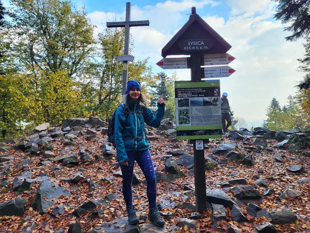 Uśmiechnięta turystka na szczycie Łysicy, 614 m n.p.m. Jesienne liście i kamienie wokół.