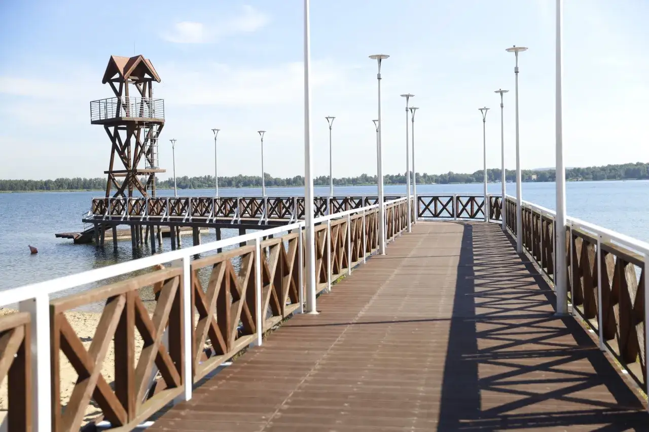 Drewniane molo z wieżą ratowniczą nad jeziorem, idealne na spacer. Zbiornik Pogoria III w letnim słońcu.