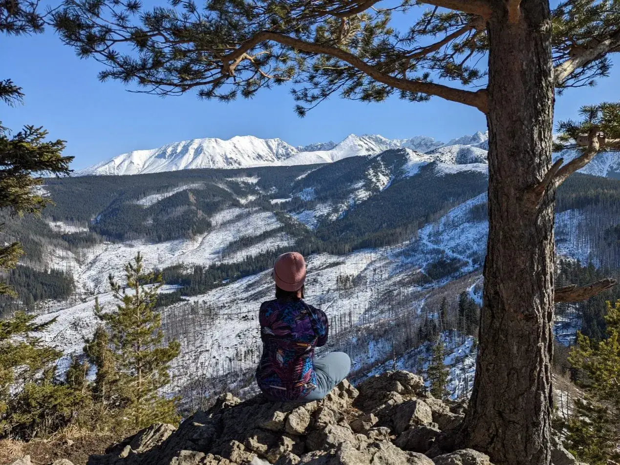 Widok na ośnieżone Tatry z punktu widokowego. Kobieta w czapce podziwia panoramę, czując magię wejścia na Nosal.