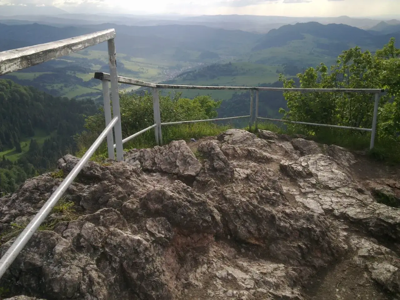 Widok z punktu widokowego na skałach w Małych Pieninach. Metalowa balustrada chroni przed upadkiem z urwiska.