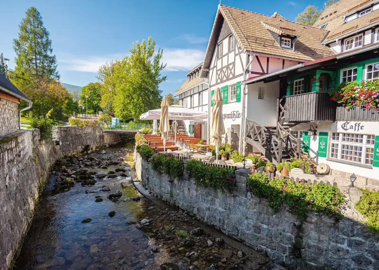 Urokliwy deptak w Szklarskiej Porębie nad kamienistym potokiem, z restauracją i kawiarnią.