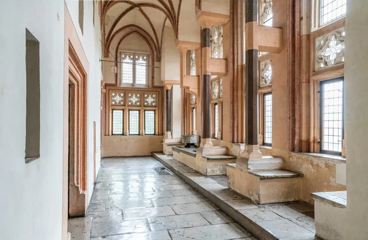 Wnętrze zamku w Malborku, z kamienną posadzką i ozdobnymi oknami. Ciekawostki o zamku w Malborku kryją się w każdym detalu.