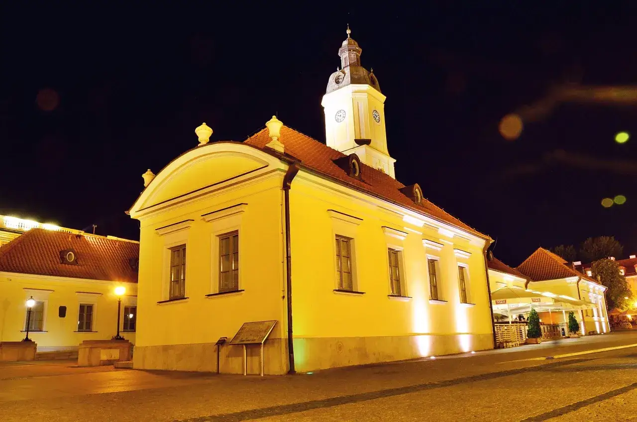 Żółty budynek ratusza z wieżą zegarową nocą na Rynku Kościuszki w Białymstoku.