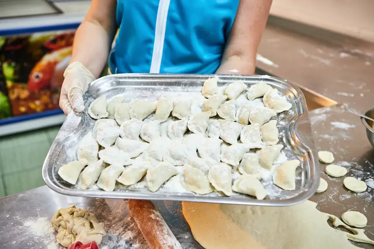 Taca z surowymi pierogami, gotowymi do zamrożenia. To świetny sposób, jak mrozić pierogi, by cieszyć się nimi później.
